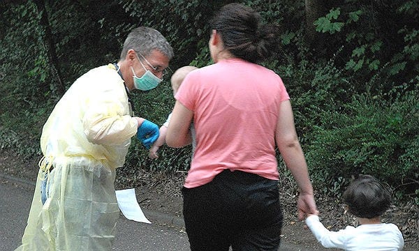 Flüchtlinge in der Erstaufnahme Bergisch Gladbach:: Ein Arzt kümmert sich um eine Familie mit Kleinkindern.