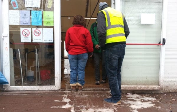 Eine DRK-Sozialarbeiterin und ein Sicherheitsmann beobachten die Putzaktion in der Aufenthaltshalle